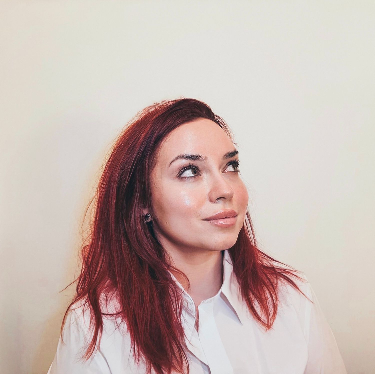 Portrait of a woman looking slightly upward with a calm expression, wearing a light shirt against a simple background.