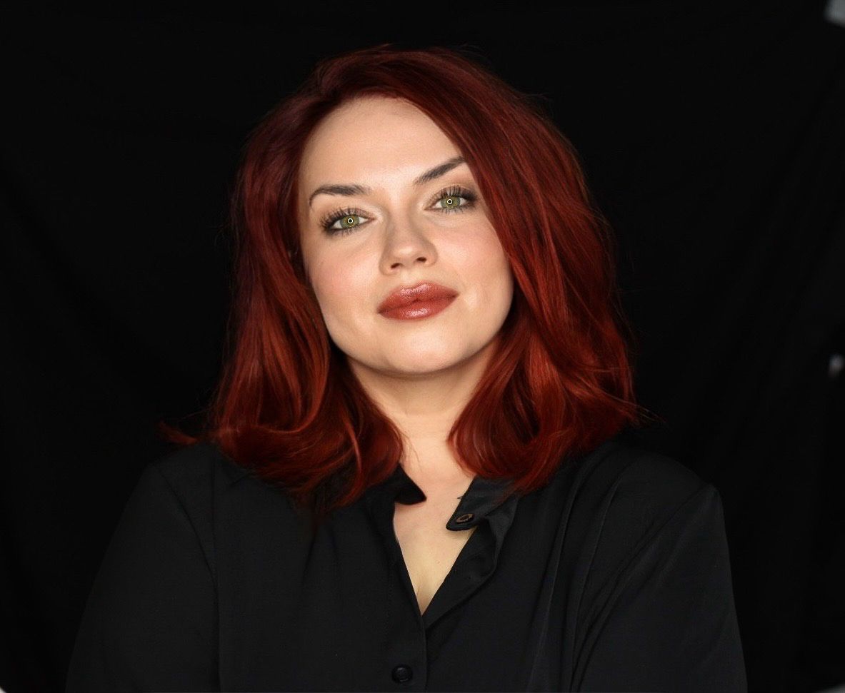Counsellor with red hair and a confident presence, standing against a dark background—professional portrait for therapy practice.