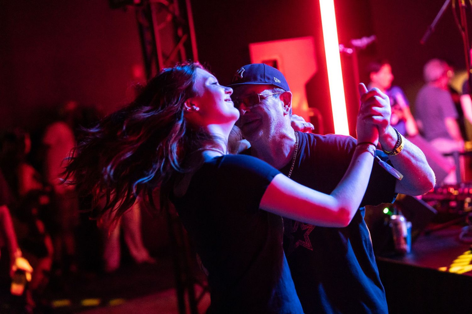 Couple dancing passionately in a dark nightclub with dramatic red lighting and band performing in the background.