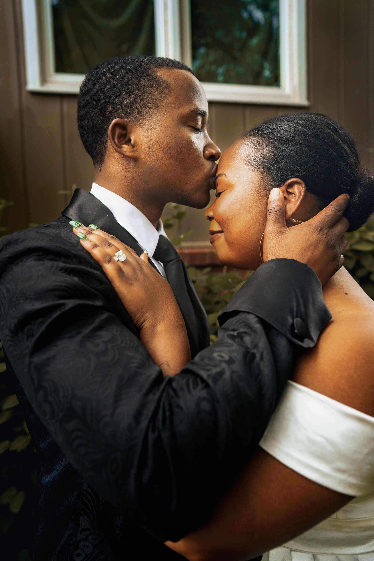 A tender moment shared between a couple in formal attire as they embrace during what appears to be their wedding day.