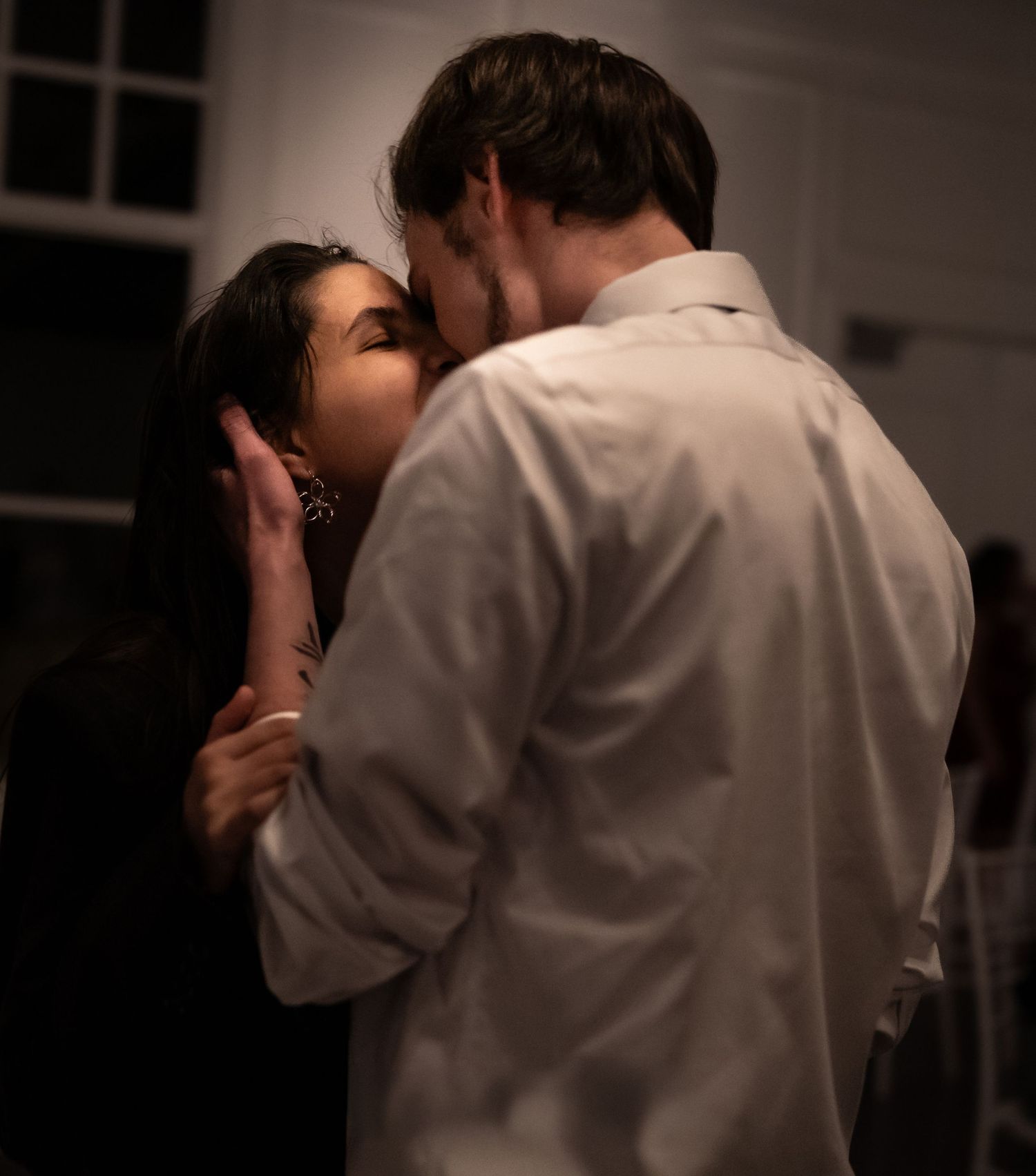 Intimate romantic moment between couple in dimly lit room.