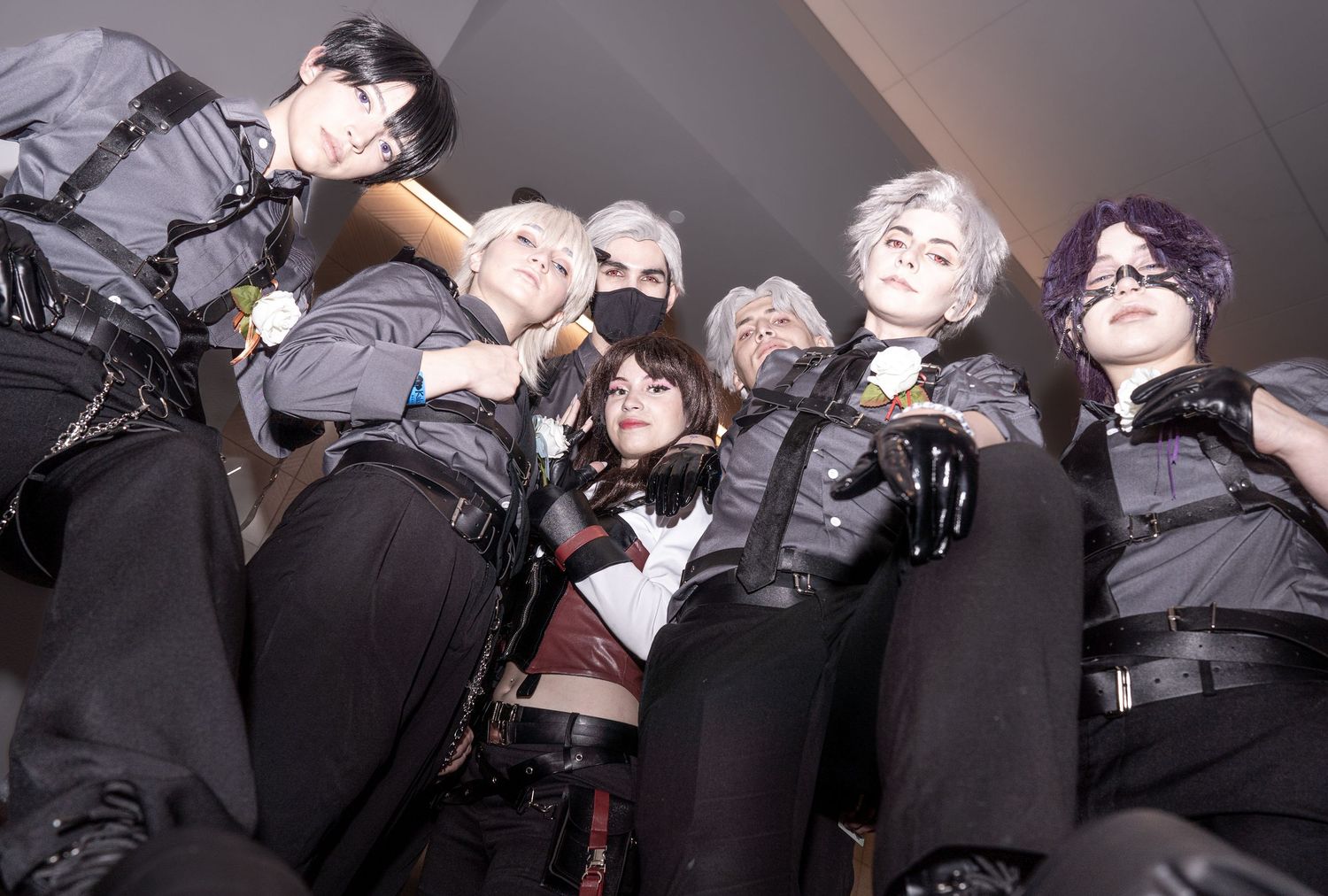 Group of performers dressed in black attire strike dramatic poses while creating a theatrical tableau effect on stage.