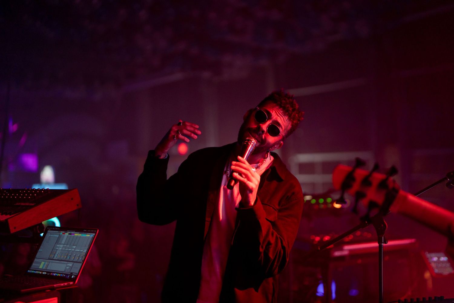Performer singing on stage bathed in dramatic red lighting during show.