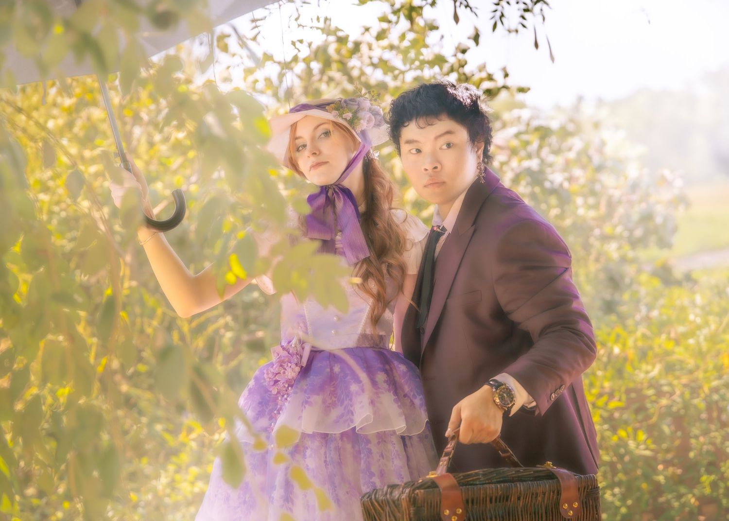 A couple in vintage clothing pose together against a sunlit backdrop of golden autumn foliage.