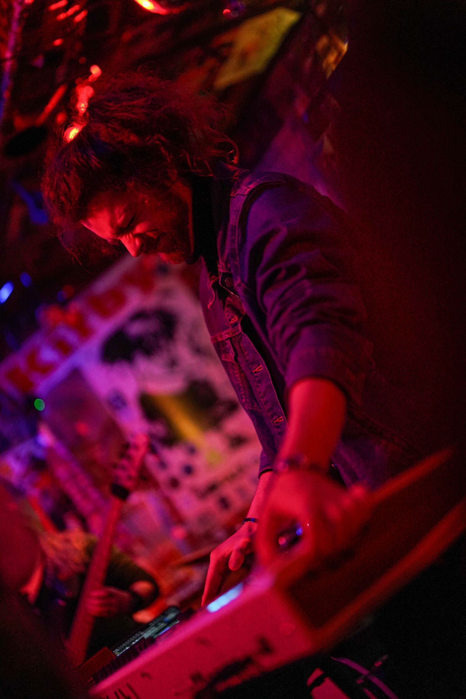 DJ performing at a nightclub under dramatic red and purple lighting effects during a live set.