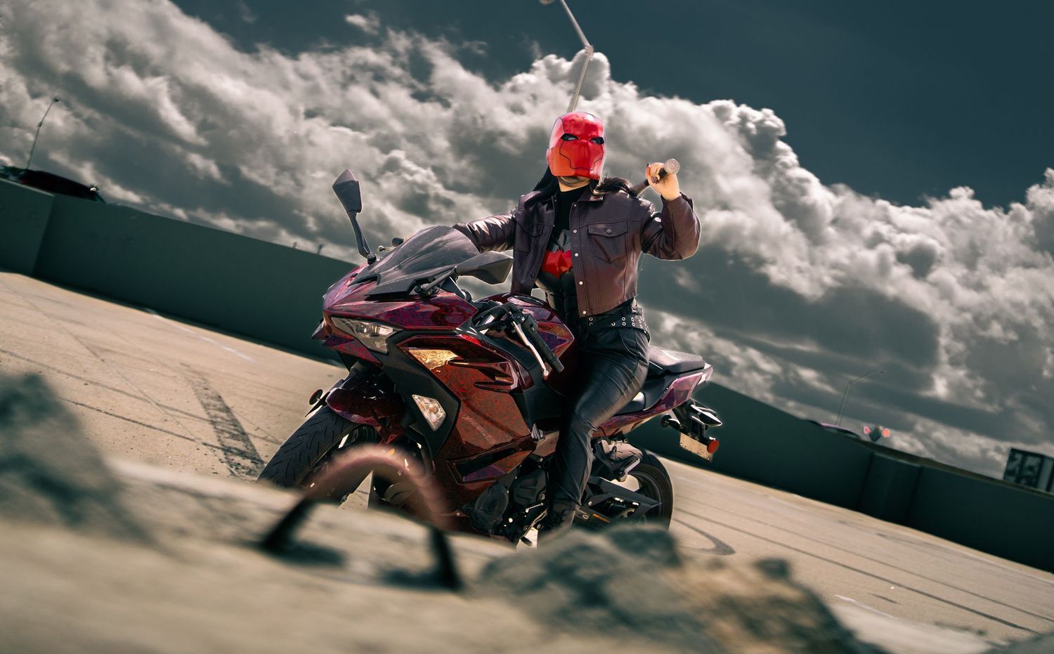 Motorcyclist leans into corner on mountain road under dramatic cloudy sky during thrilling ride.