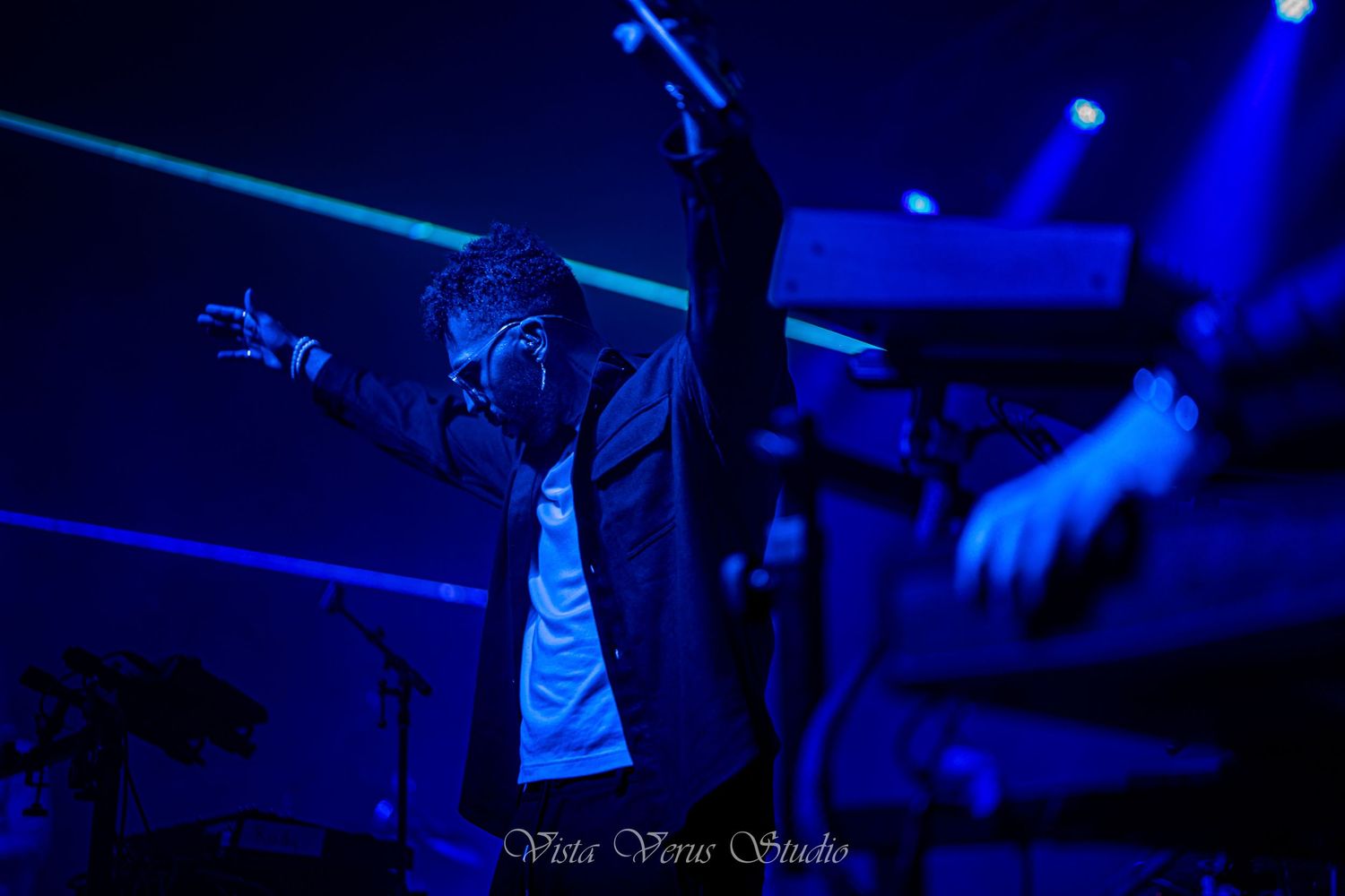 Silhouette of performer on stage illuminated by dramatic blue concert lighting.