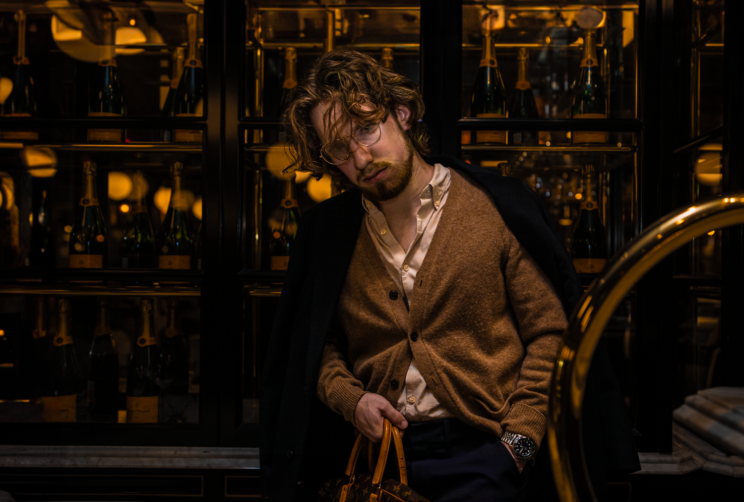 Moody portrait of person in brown sweater at dimly lit bar.