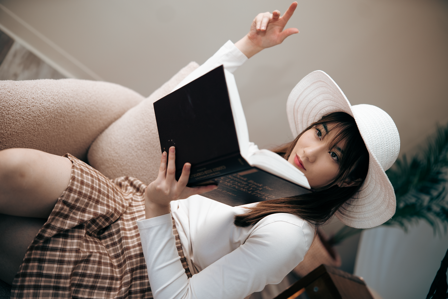 Casual indoor portrait with white hat and book.