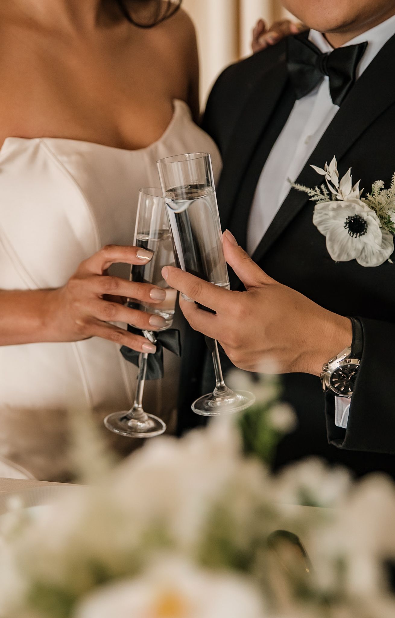 Close-up of champagne glasses clinking during a formal wedding toast.