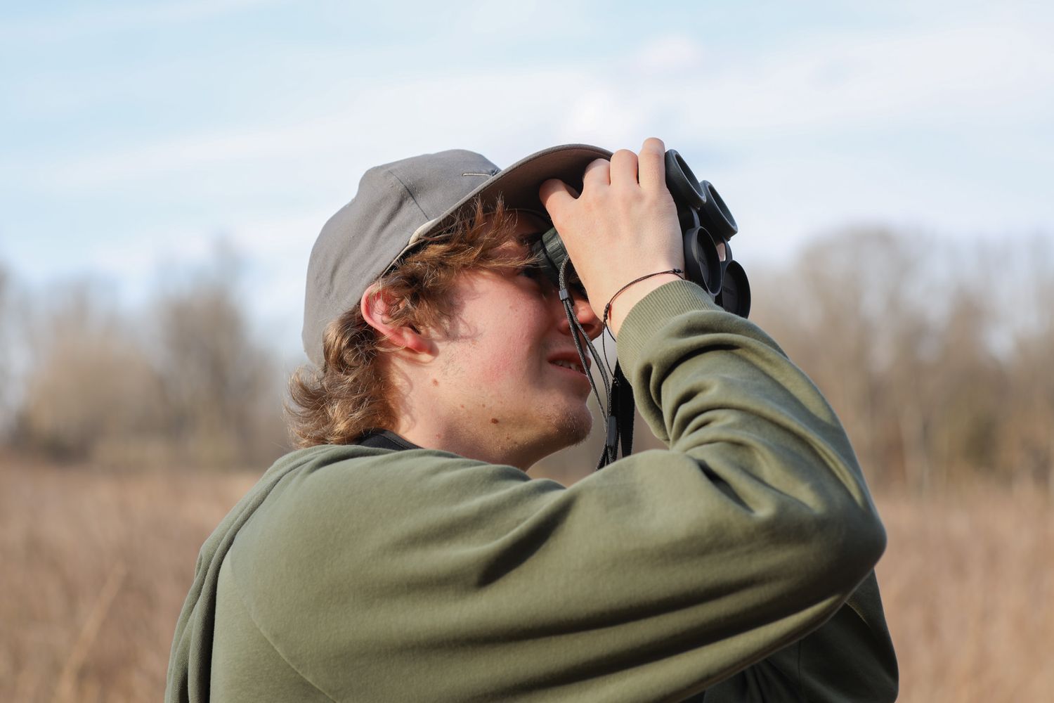 Christian Hawn, 17, searches for birds through his binoculars