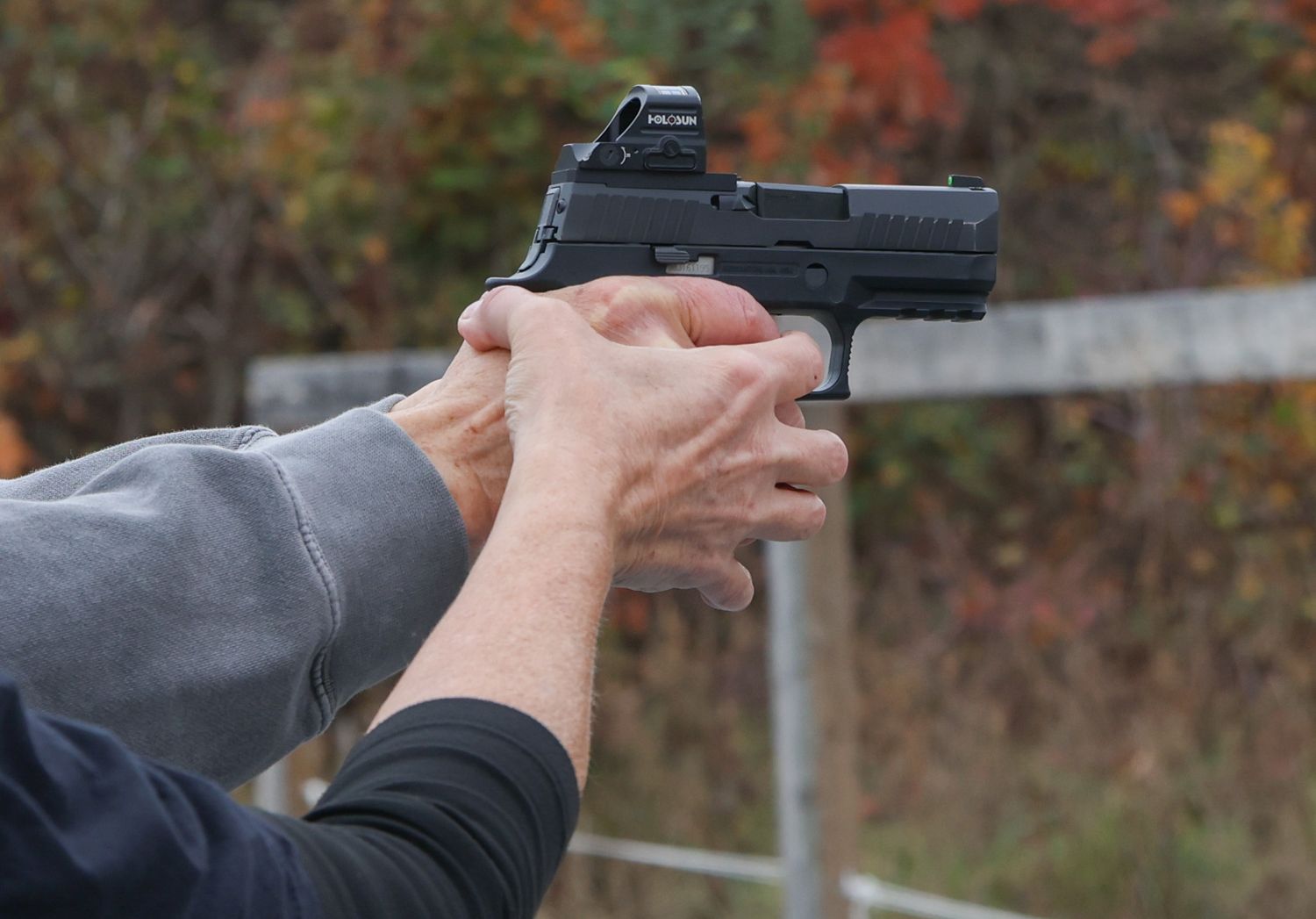 Amy Hess, front, guides Janet Bezler’s hand to aim a gun during a private session