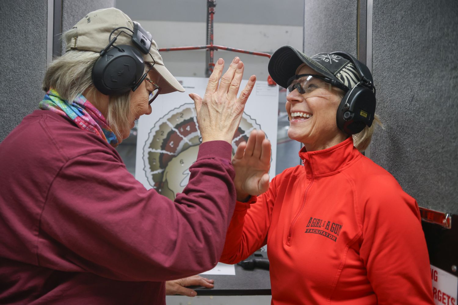 C.E., left, a member of the Columbia section of the A Girl and A Gun club, high fives Amy Hess after counting points on her target