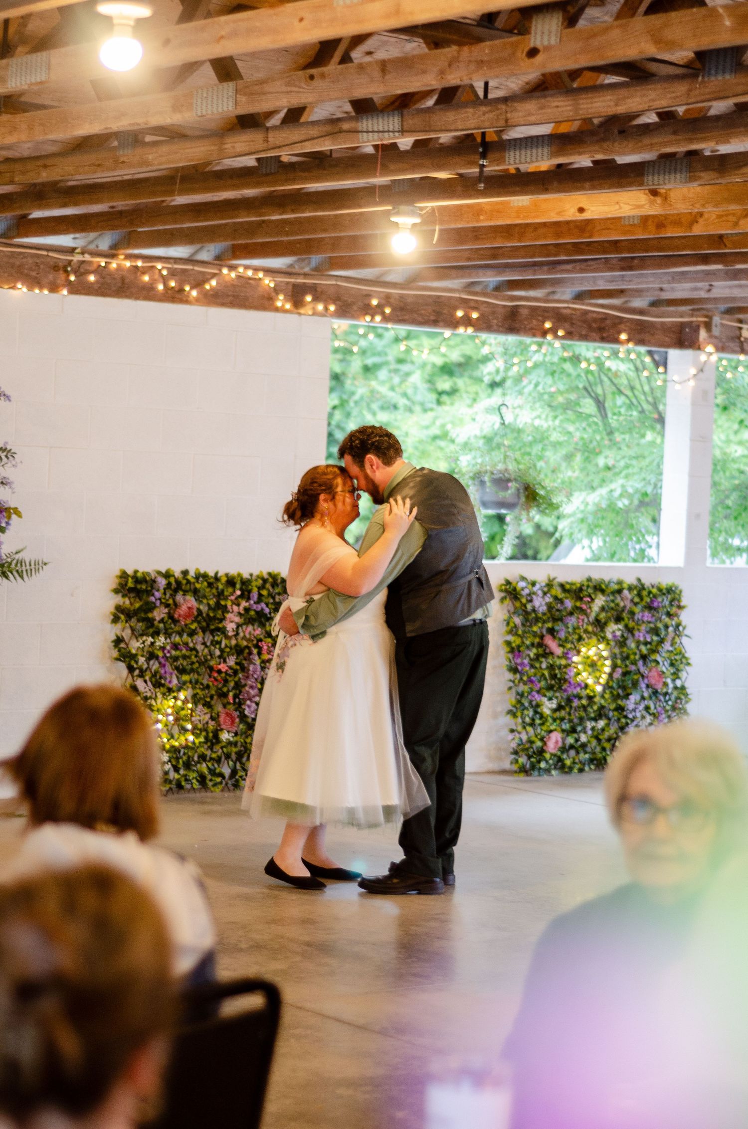 First dance moment captured in a rustic venue with wooden beam ceiling and natural lighting. Wedding photos by KM Conceptions Photography