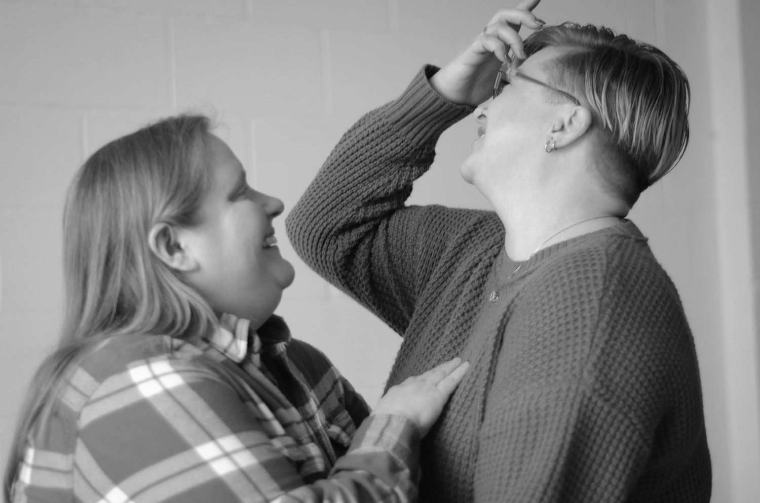 Black and white portrait of couple playfully interacting in casual sweaters.