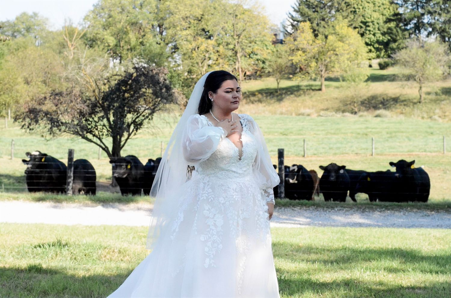Bride in white lace dress walking through a sunny green field. Wedding photos by KM Conceptions Photography in Columbus, OH.
