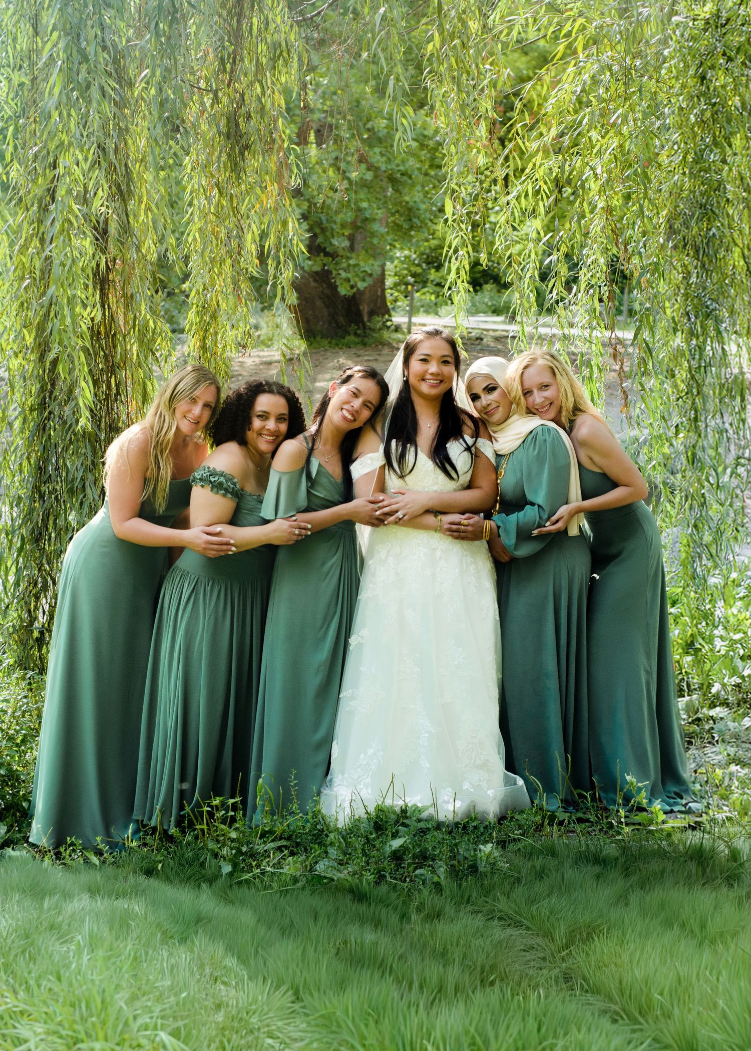 Wedding party in emerald green dresses poses together under a willow tree. Wedding photos by KM Conceptions Photography in Columbus, OH.