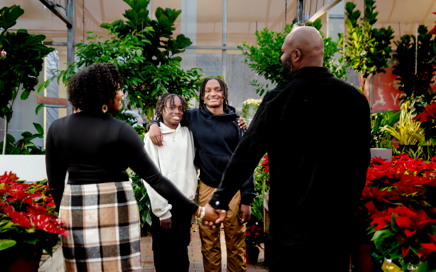 Family gathering among festive poinsettia displays and holiday greenery. Photos by KM Conceptions Photography.