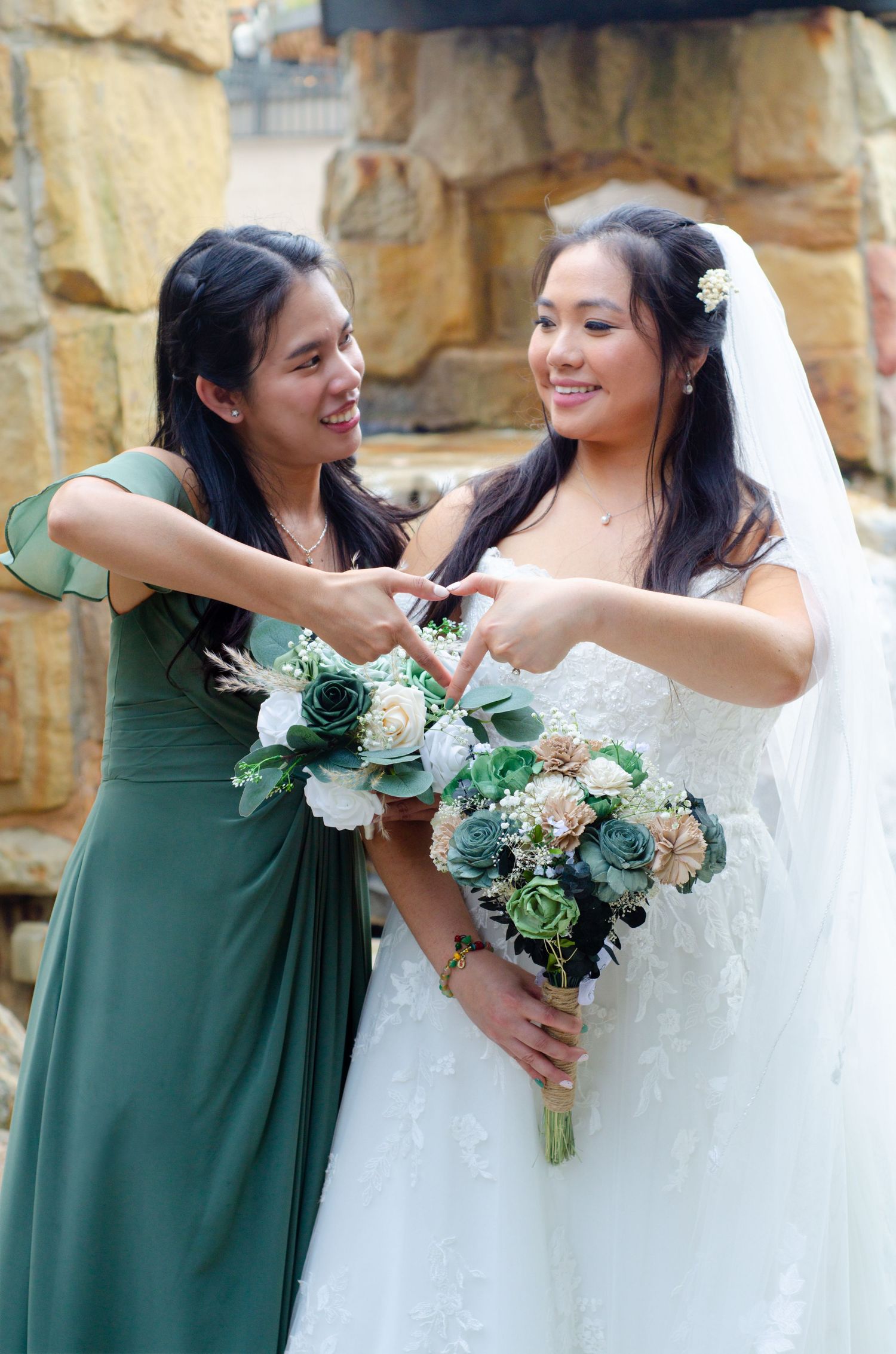 Joyful wedding moment showing bridesmaids in emerald green dresses embracing and laughing with the bride in white.