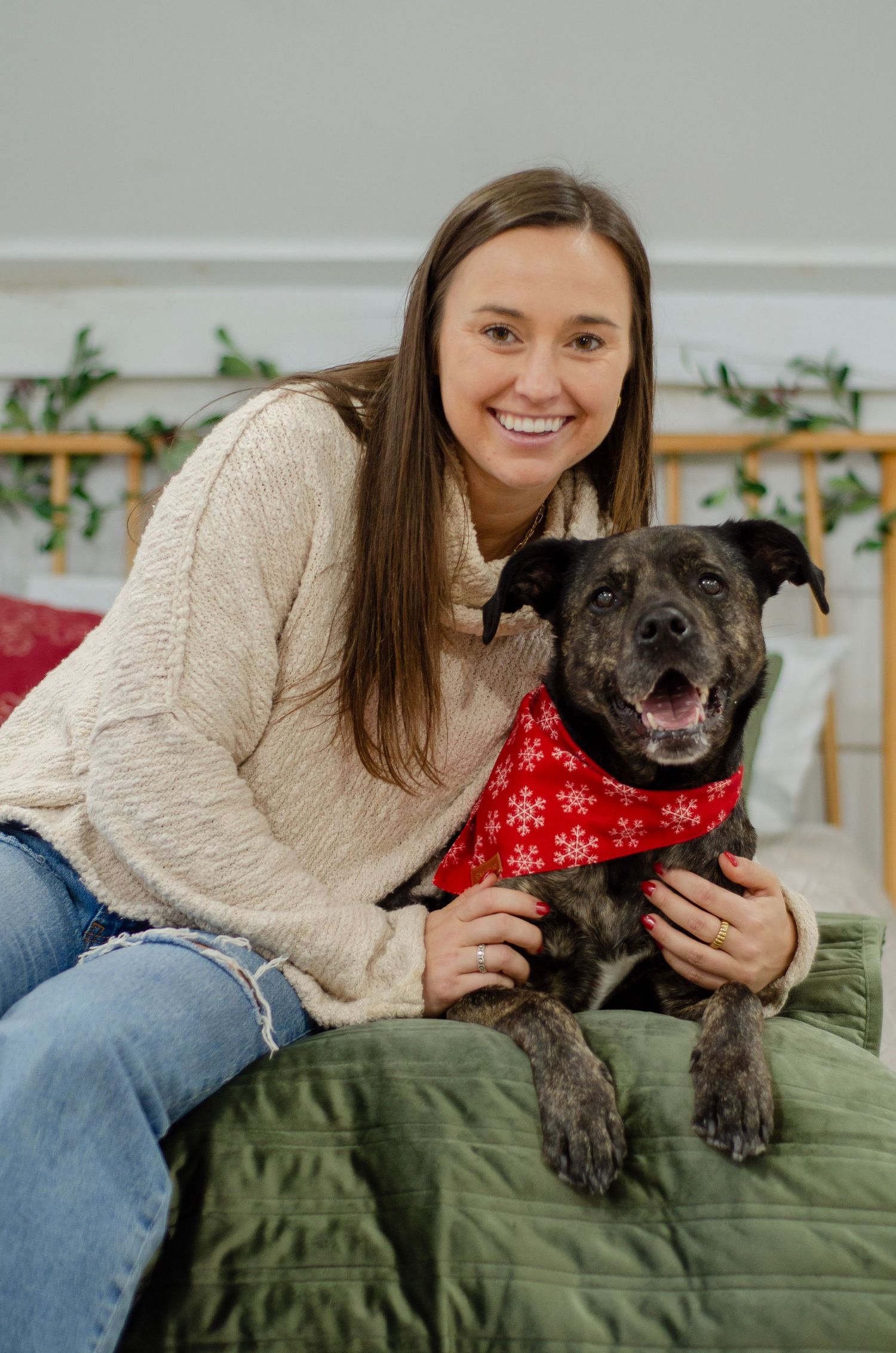 A cozy indoor portrait with a happy black dog wearing a red bandana.