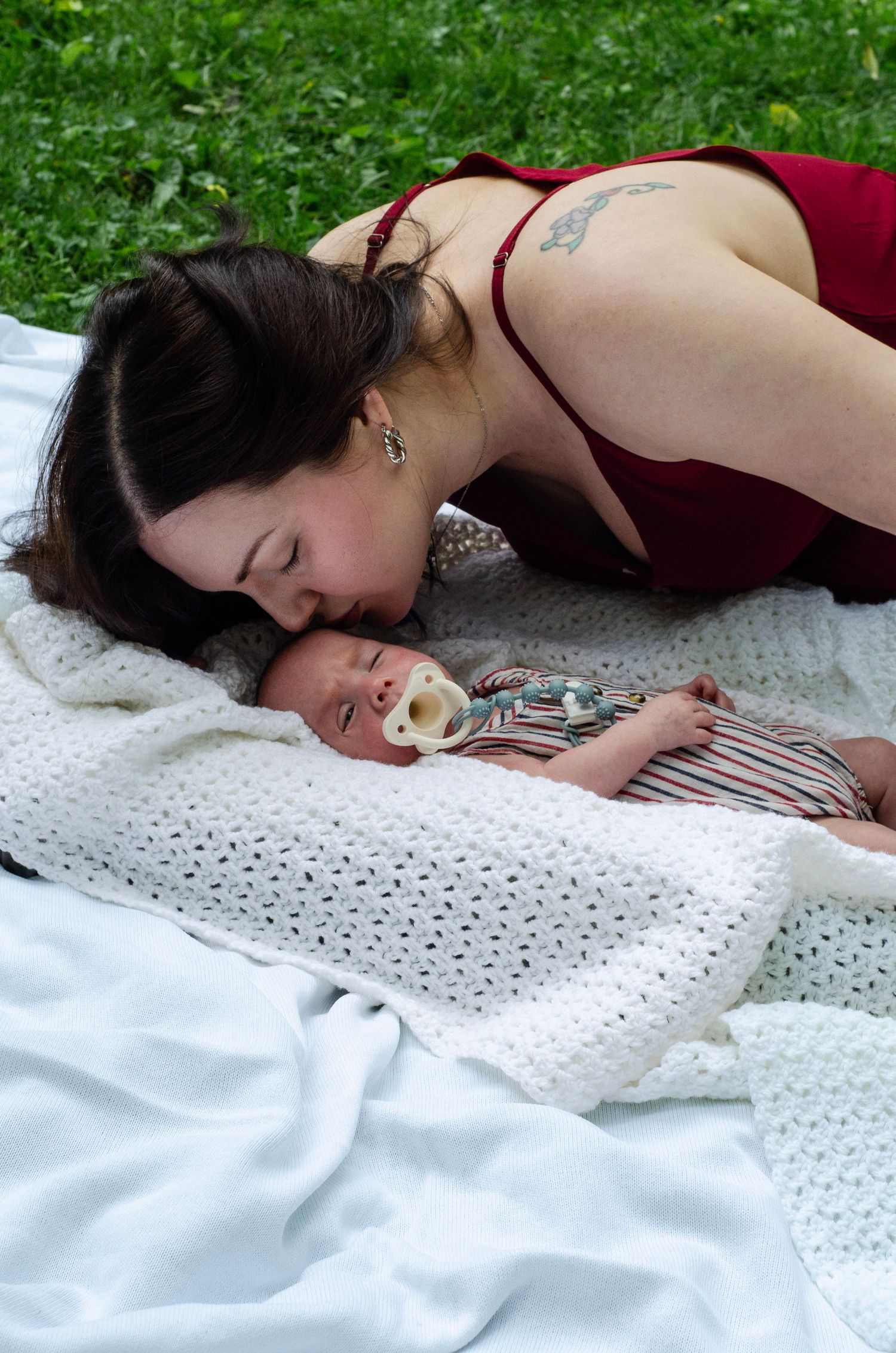 An intimate moment between parent and baby lying on a white blanket outdoors. Newborn photos by KM Conceptions Photography in Columbus, OH.