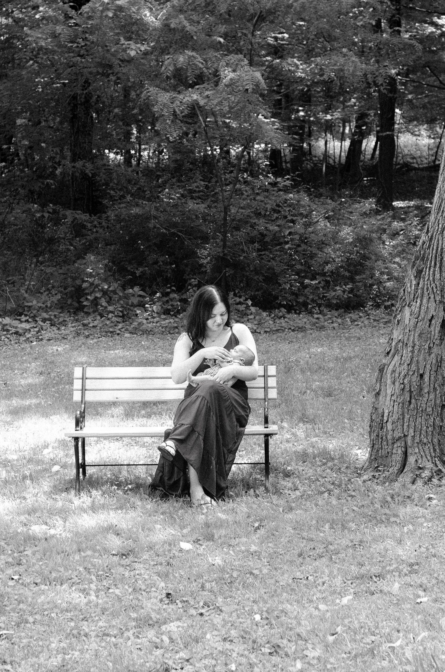 A sequence of black and white photos showing someone sitting alone on a park bench surrounded by trees. Newborn photos by KM Conceptions.