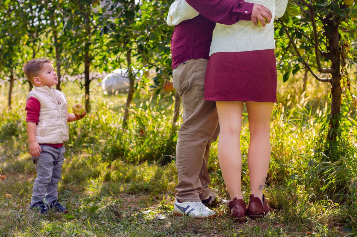 Casual outdoor family photoshoot with legs and feet visible against grass and trees. Family photos by KM Conceptions Photography.