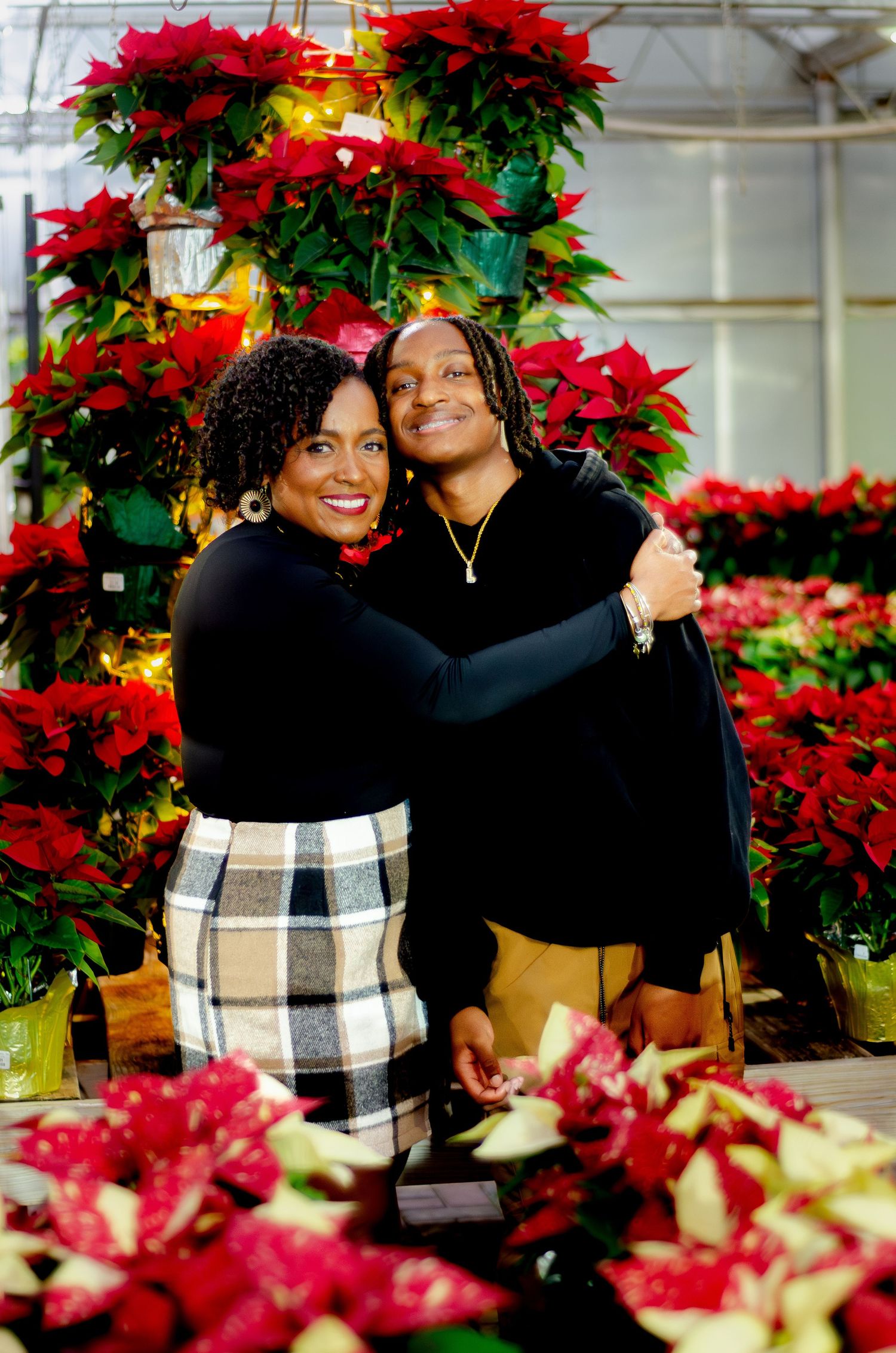 Joyful holiday portraits surrounded by bright red poinsettias and seasonal decorations. Photos by KM Conceptions Photography.