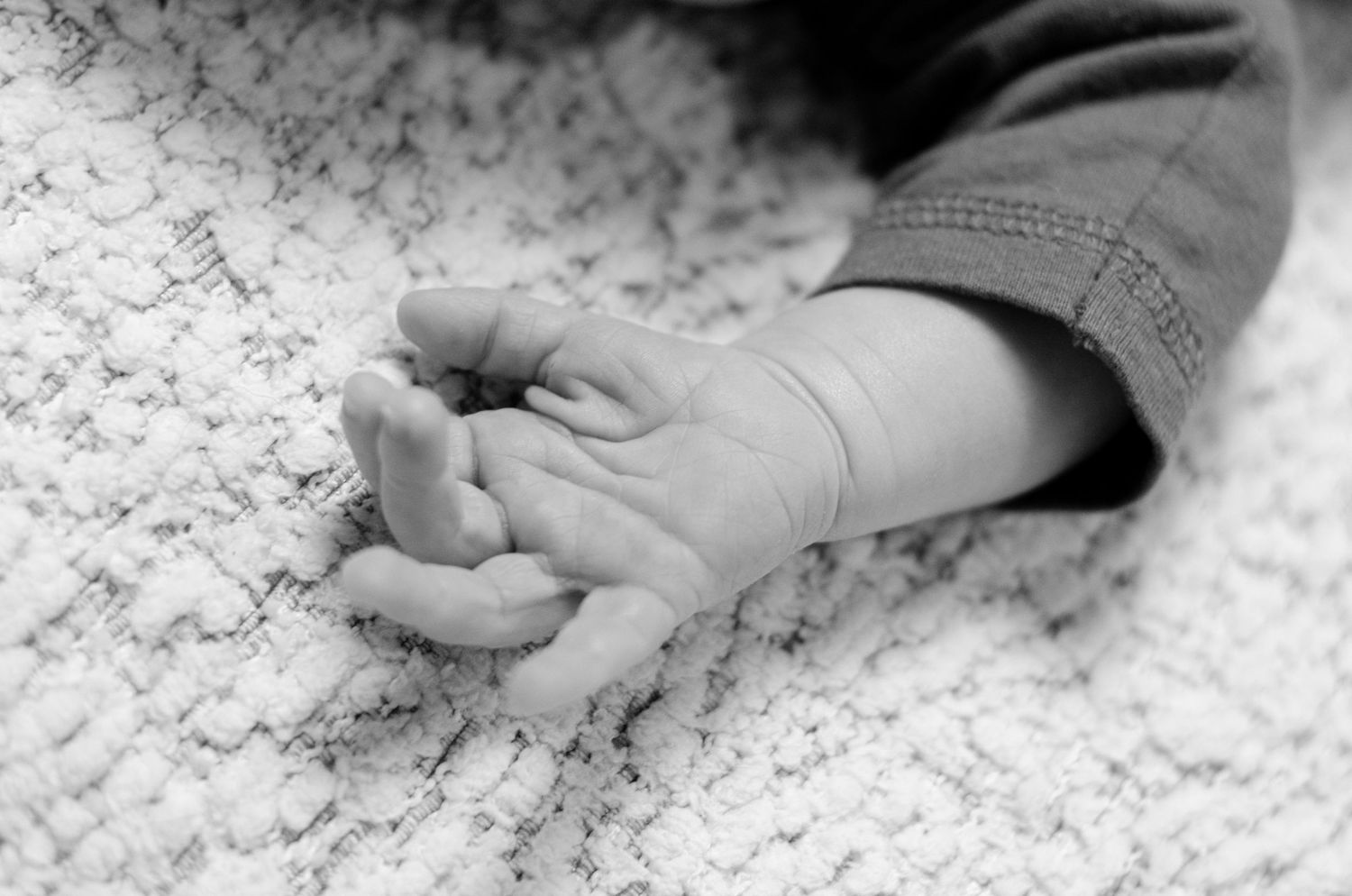 Close-up black and white photo of tiny feet against textured white surface. Newborn photography in Columbus, OH