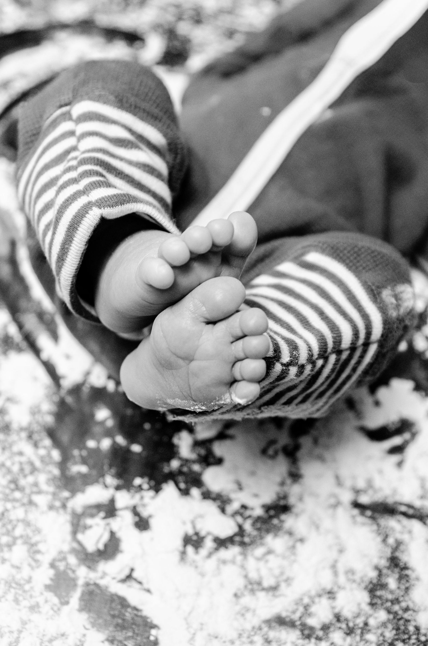 Close-up of tiny feet in striped pajamas surrounded by flour. Newborn photography in Columbus, OH