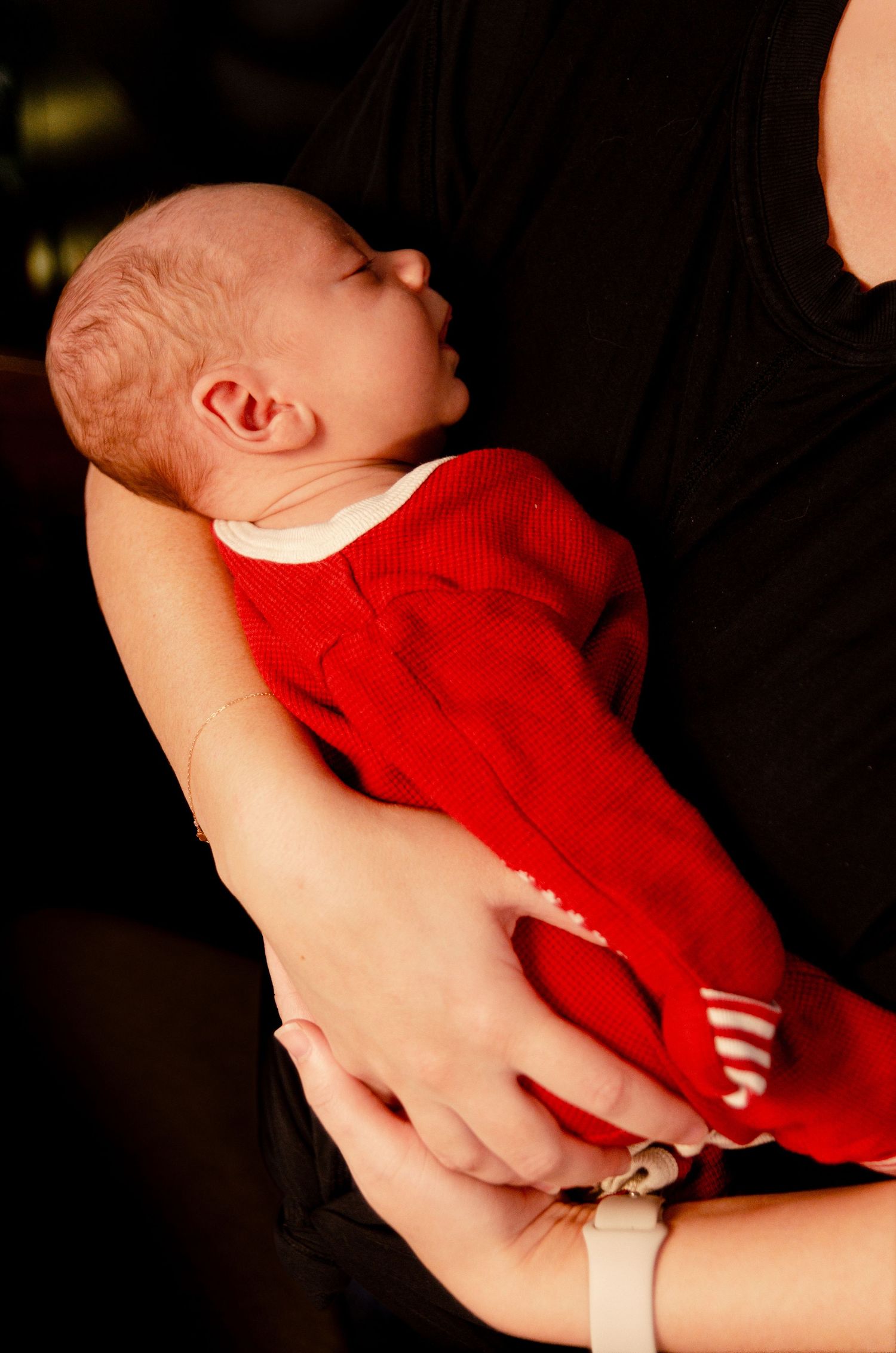 Baby wearing red clothing sleeping peacefully in dark setting. Newborn photography in Columbus, OH