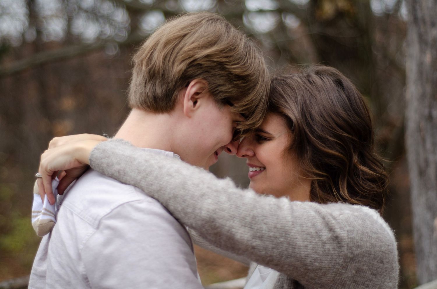 A couple embraces on a wooded path during autumn.
