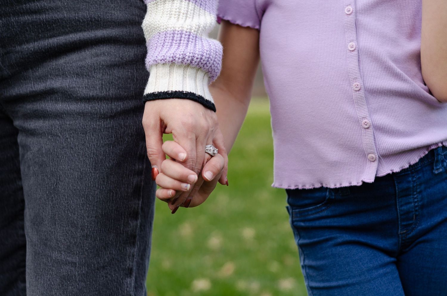 Close-up of hands holding together against casual clothing background.