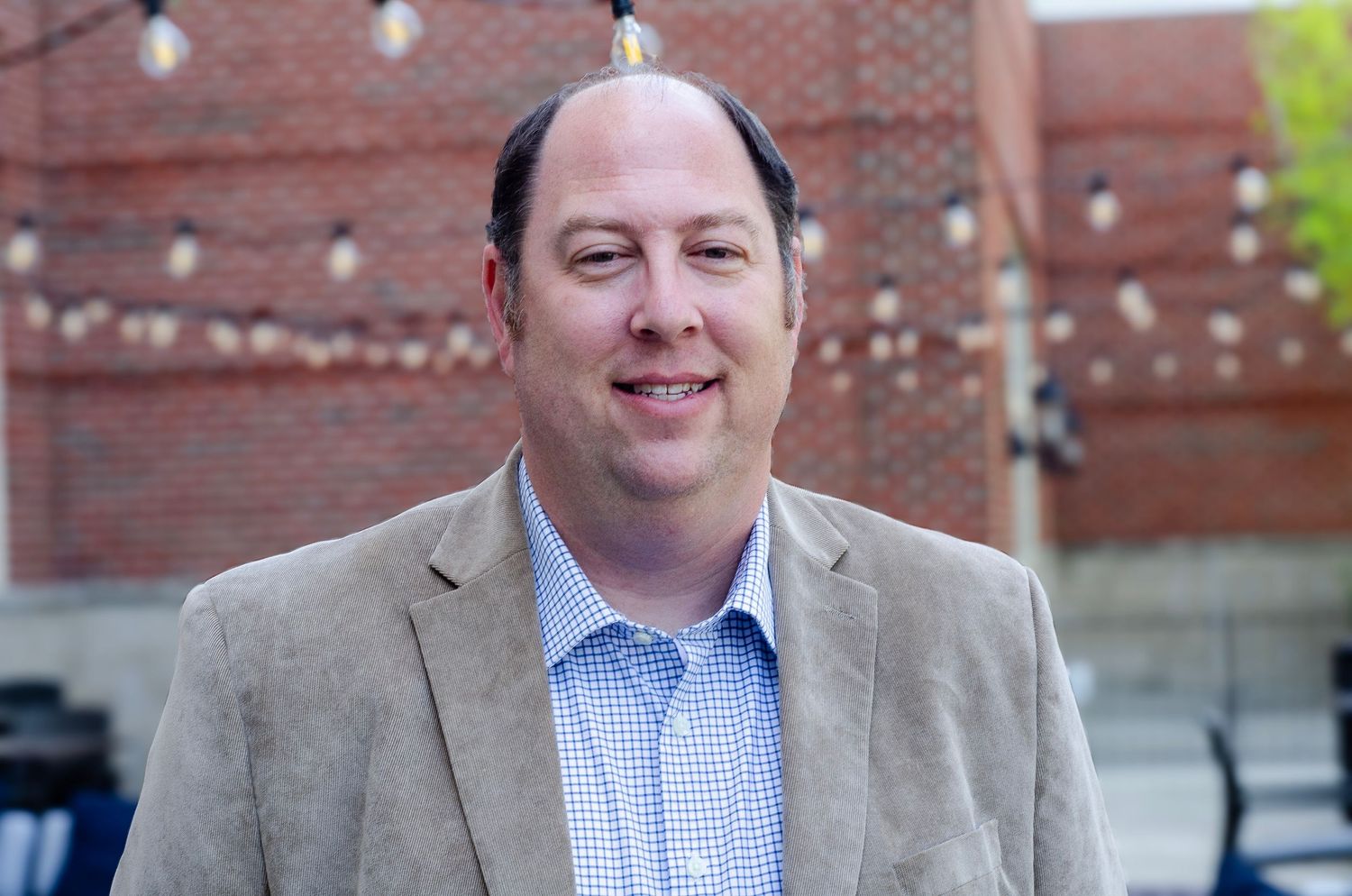 Professional headshot series showing expressions in business attire against brick wall.