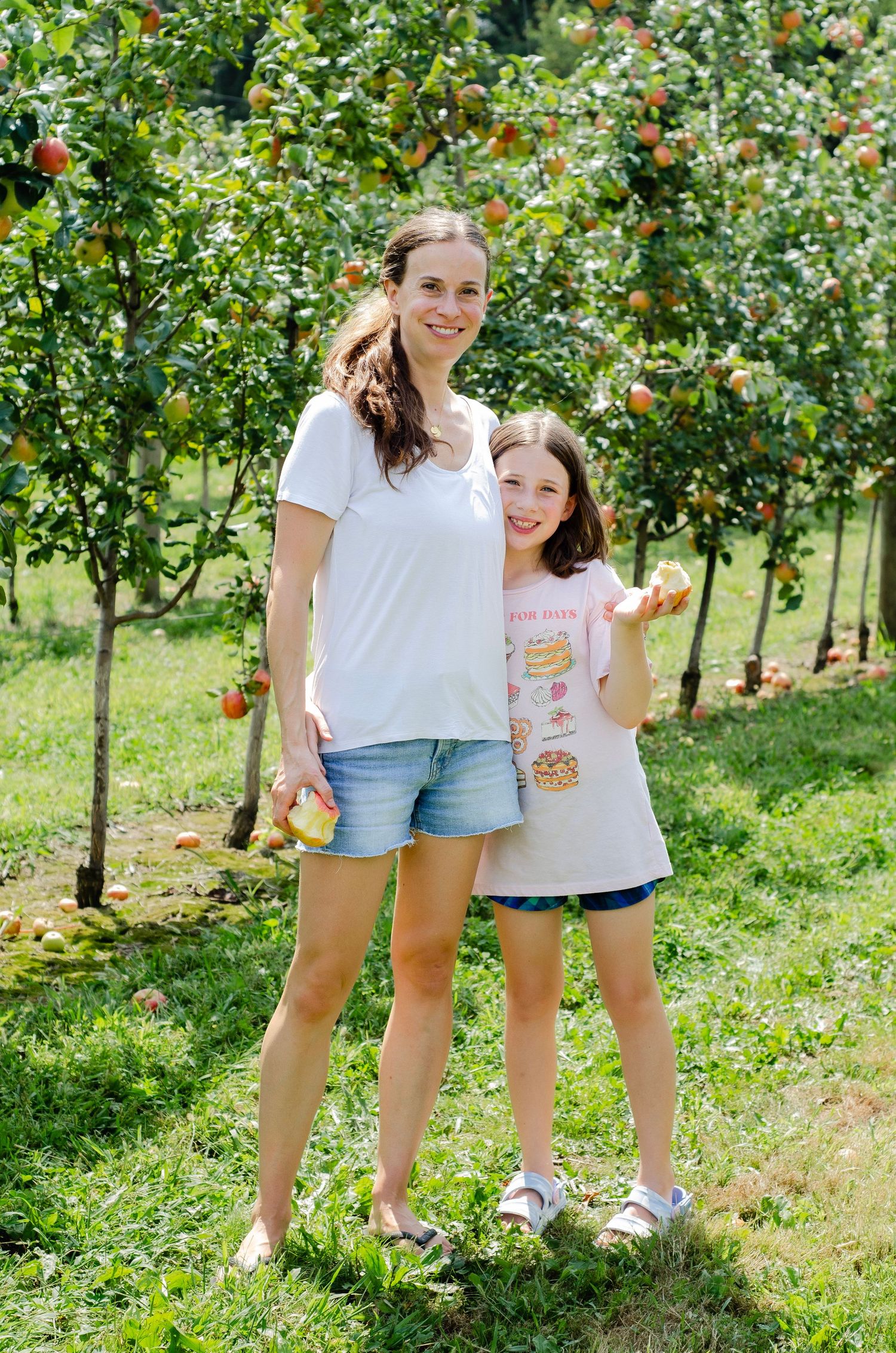 Mom and daughter standing between rows of apple trees. Family photos by KM Conceptions Photography in Columbus, OH.
