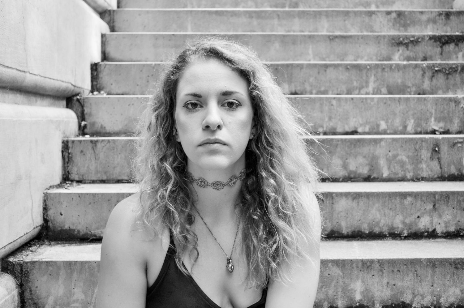 Black and white portrait on concrete steps with dramatic lighting.