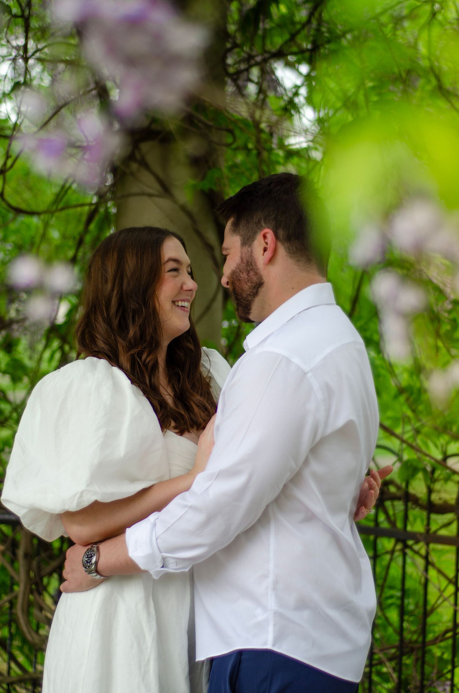 Romantic couple sharing intimate moments under blooming trees in a spring garden setting.