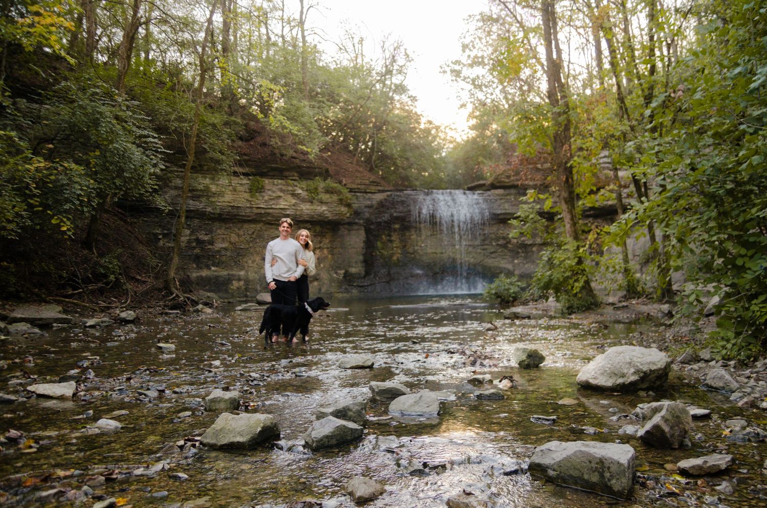 Waterfall and creek surrounded by tall limestone cliffs and autumn trees. Family photos by KM Conceptions Photography in Columbus, OH.