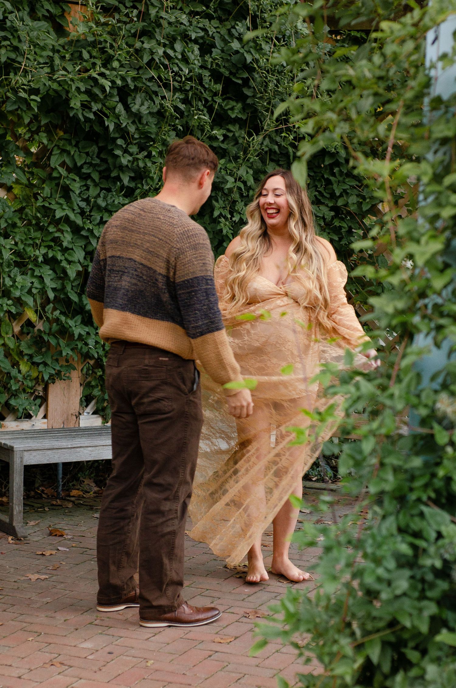 Couple sharing playful moments in a garden setting with natural greenery. Maternity photos by KM Conceptions Photography in Columbus, OH.