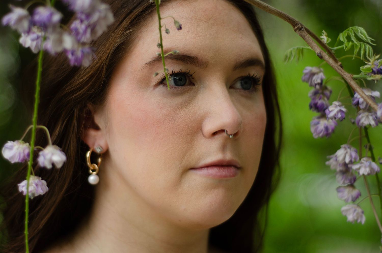 A dreamy portrait with delicate purple flowers in soft natural lighting.