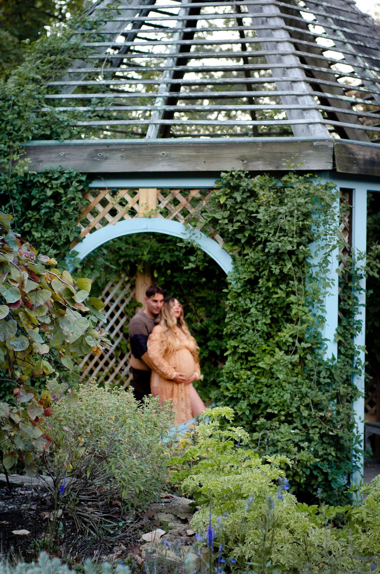 Couple embracing under a white latticed gazebo at Inniswood Garden in Westerville, OH.