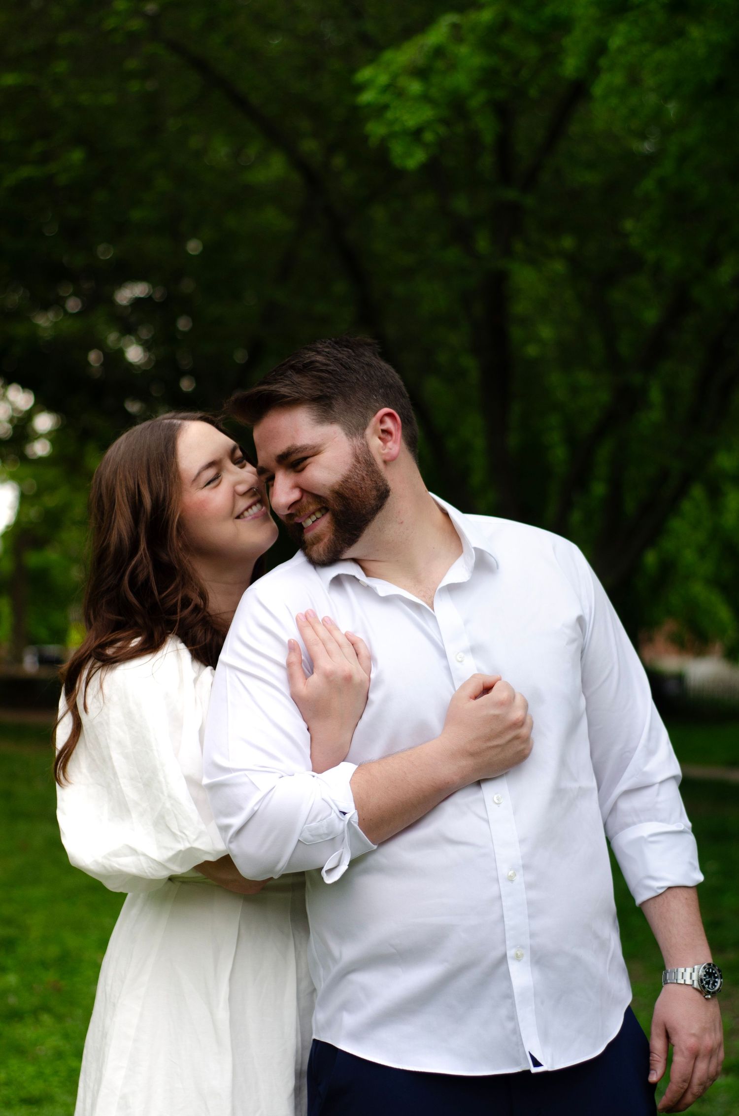 Affectionate couple sharing intimate moments in a verdant park setting.