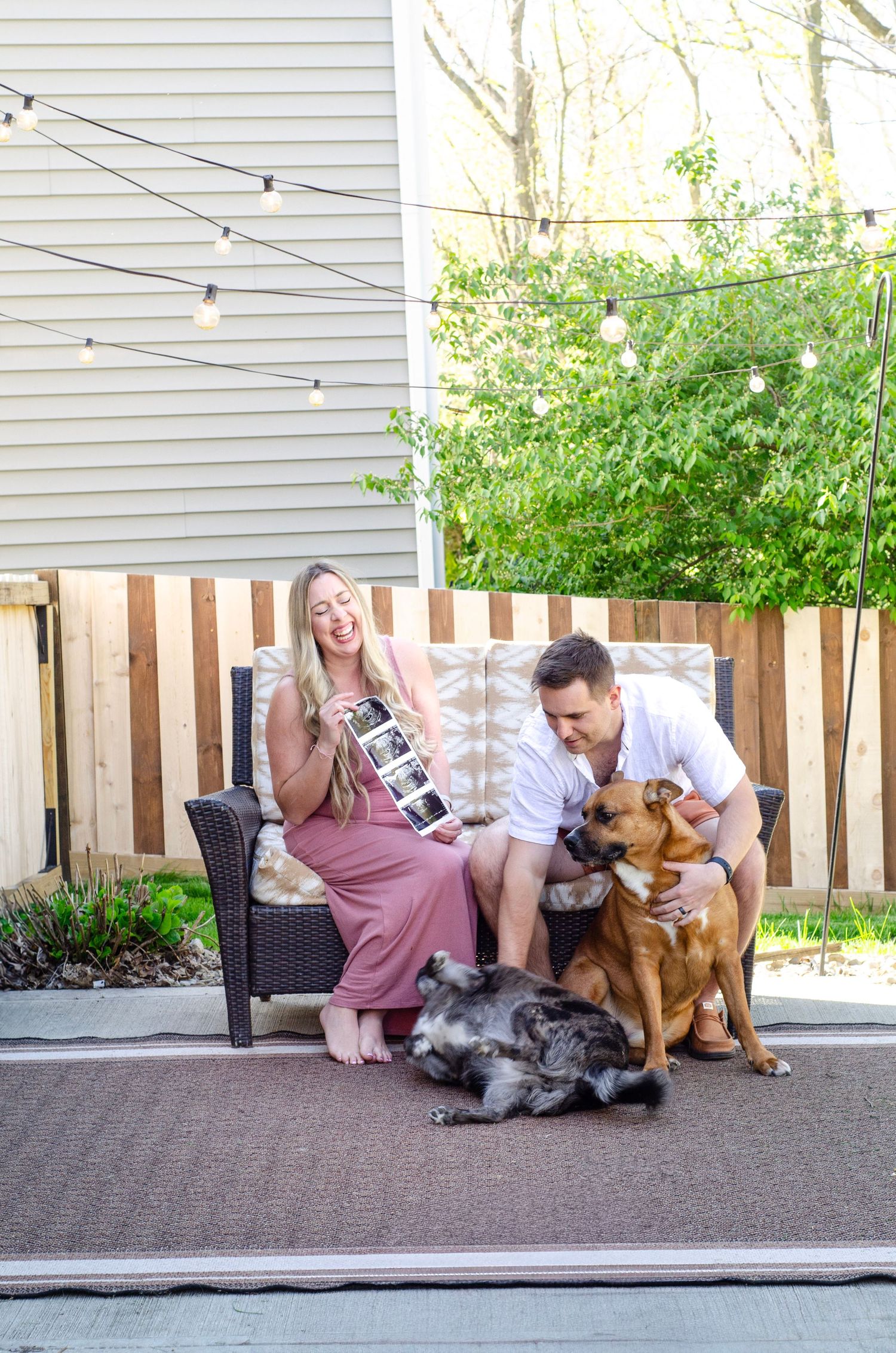 A couple sits on their patio with their two dogs enjoying an outdoor moment together.