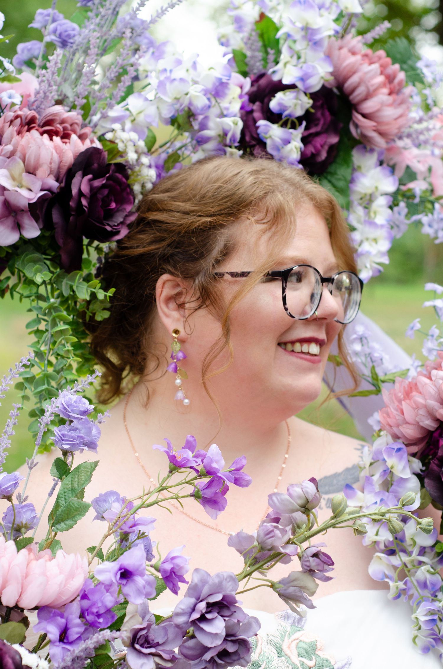 Delicate purple and pink floral arrangements frame a romantic wedding portrait in a garden setting. Weddin photos by KM Conceptions.