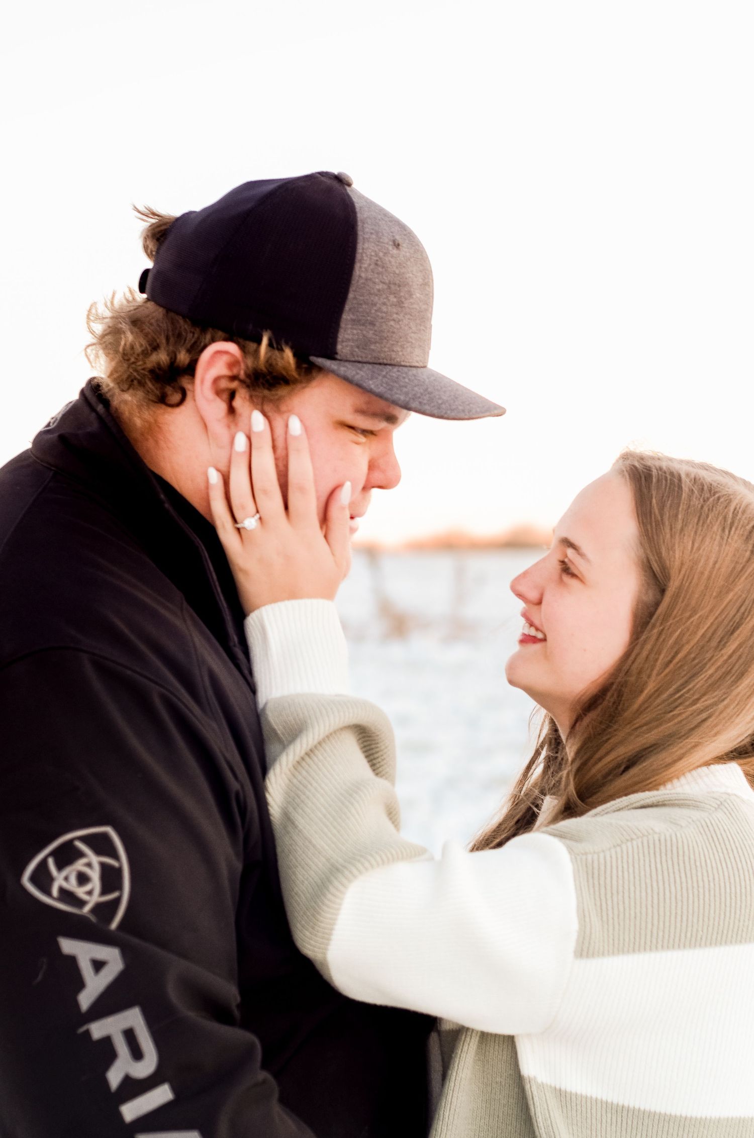 Romantic couple sharing an intimate moment in winter wearing cozy sweaters and a baseball cap.
