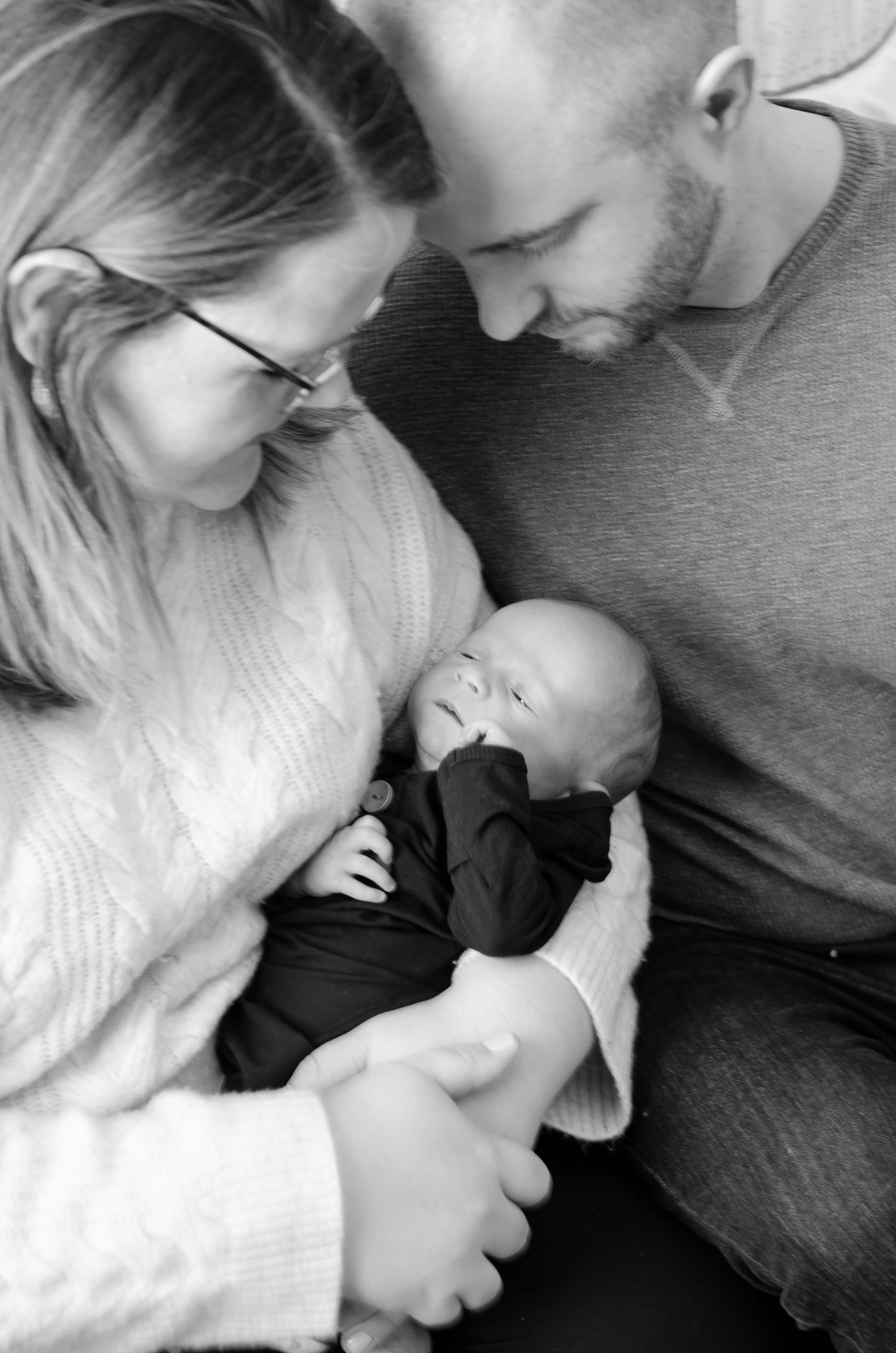 Black and white photo series showing intimate moments between a family in tender embrace. Newborn photos by KM Conceptions Photography