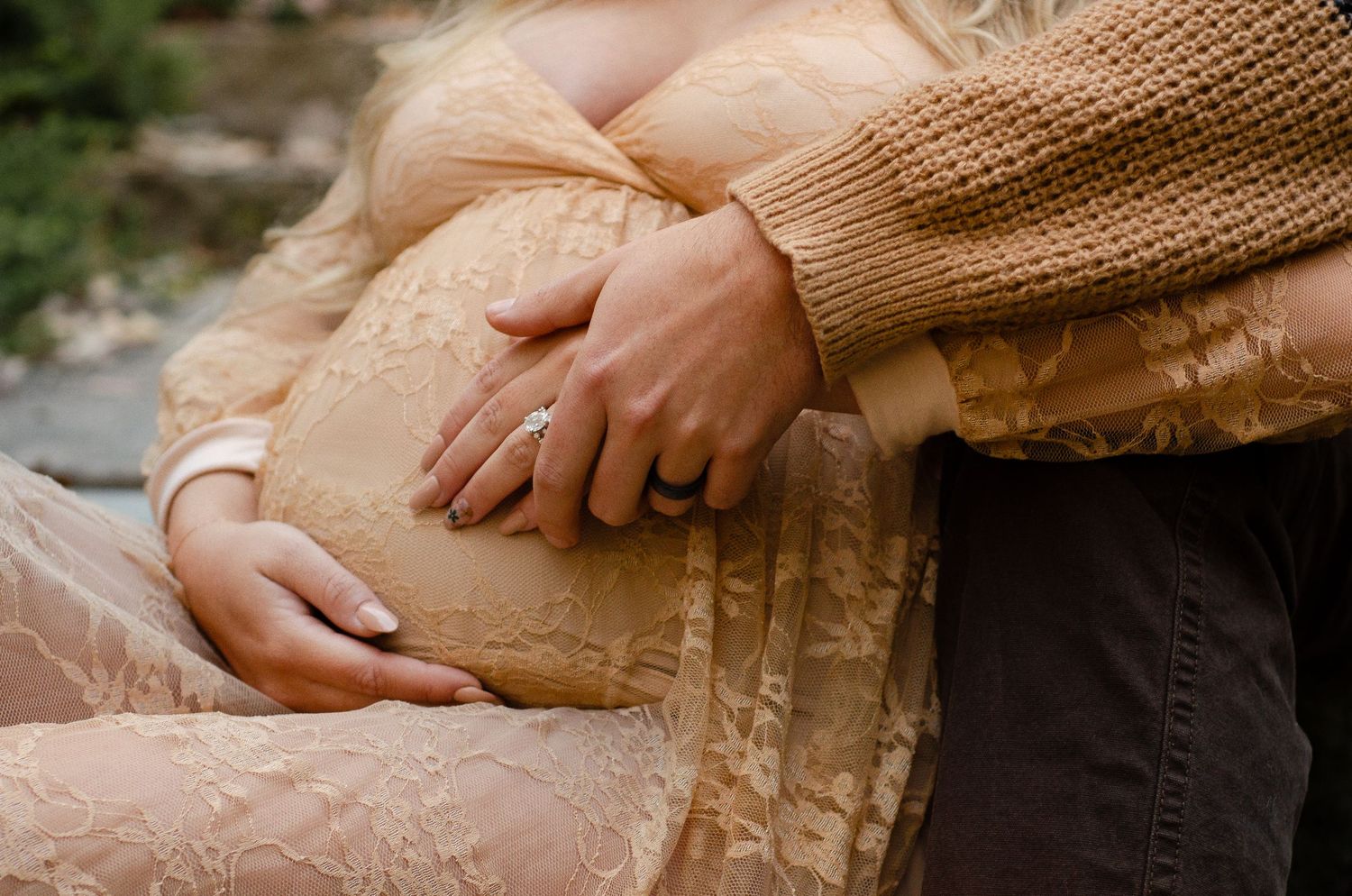 Hands gently caress a delicate lace dress in warm sunlight. Maternity photos by KM Conceptions Photography in Columbus, OH.