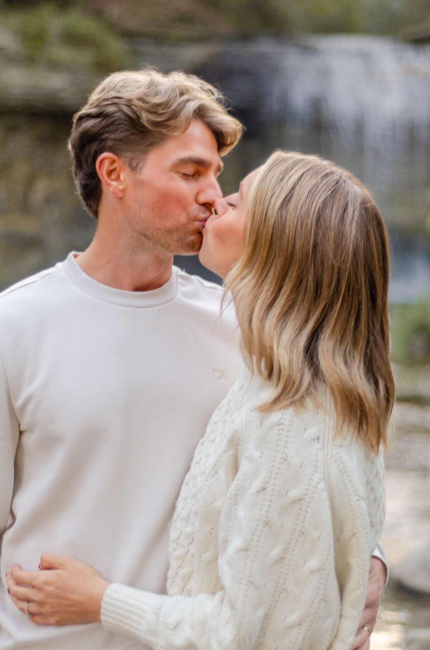 Couple in white sweaters sharing intimate moment by waterfall. Family photos by KM Conceptions Photography in Columbus, OH.