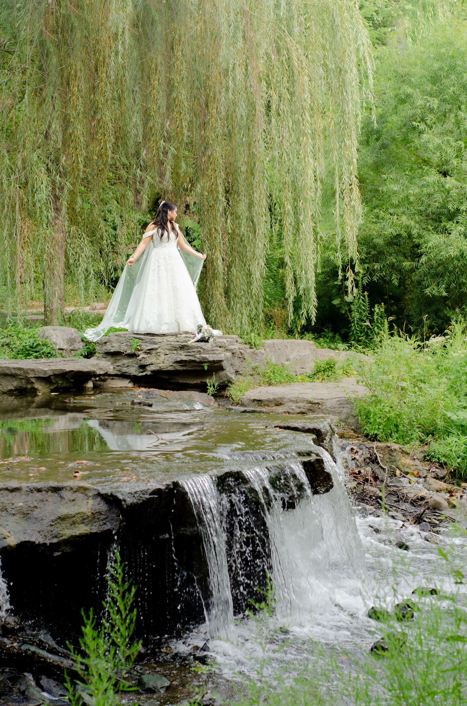 Wedding dress silhouette photographed in sequence against a scenic waterfall and weeping willow tree backdrop.