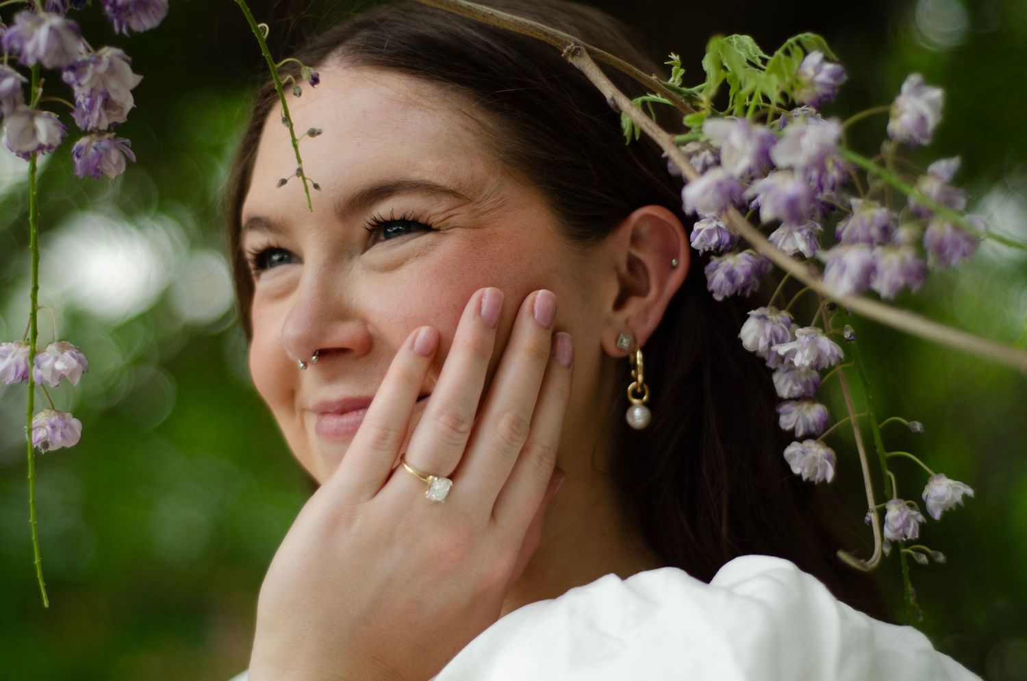 A bride smiles joyfully under blooming blossoming branches in a spring wedding portrait. Wedding photos by KM Conceptions Photography